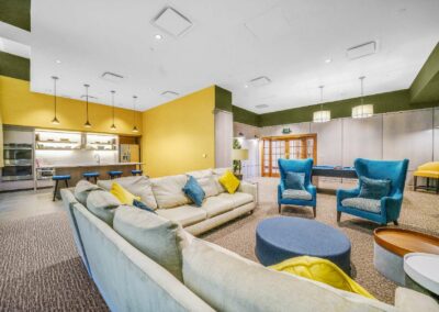 Newly renovated resident lounge with seating area and kitchen at the Packard Motor Car Building apartment community, ideal for events and relaxation.