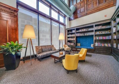 Center City apartment community, Packard Motor Car Building resident library with large windows, seating area, and built-ins filled with books