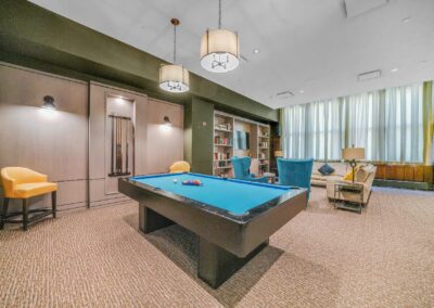 Renovated apartment building game lounge with pool table and large tv with seating area at the Packard Motor Car Building in Center City